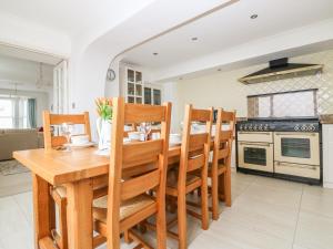 cocina y comedor con mesa de madera y sillas en Panoramic Cottage en Brixham