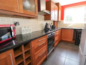 a kitchen with wooden cabinets and a black counter top at West Shore Cottage in Llandudno