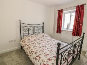 a bed in a bedroom with red curtains and a window at Welymora in Pwllheli