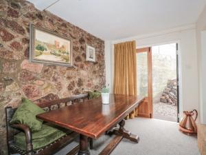 a dining room with a wooden table and a stone wall at Lilac Cottage in Great Malvern