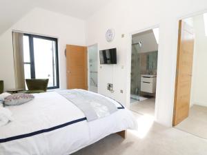 a white bedroom with a large bed and a bathroom at 7 Ocean Gateway in Hythe