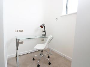 a glass desk with a white chair and a lamp at 7 Ocean Gateway in Hythe