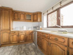 eine Küche mit Holzschränken und Spüle und einem Fenster in der Unterkunft Woodhead Farm Cottage in Penrith + 13 Fotos