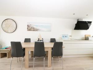 a dining room table with chairs and a clock on the wall at 7 Ocean Gateway in Hythe