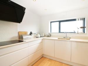 a kitchen with white cabinets and a window at 7 Ocean Gateway in Hythe