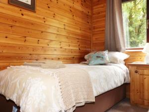 1 dormitorio con 1 cama en una pared de madera en Oak Lodge, en Falmouth