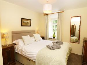 - une chambre avec un lit et un miroir dans l'établissement Rose Cottage, à lower hawthwaite