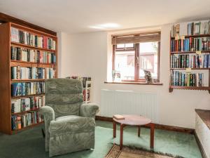 een woonkamer met een stoel, een tafel en boekenplanken bij The Courtyard in Kington