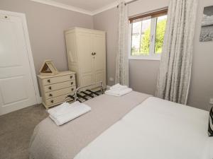 a bedroom with a bed and a dresser and a window at Manor House in Warkworth