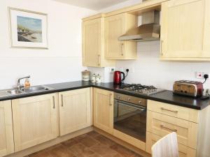 a kitchen with wooden cabinets and a sink and a stove at 5 Chandlers Yard in Burry Port