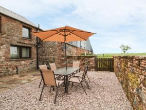 ein Tisch und Stühle mit einem Sonnenschirm auf einer Terrasse in der Unterkunft Woodhead Farm Cottage in Penrith
