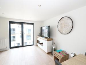 a living room with a tv and a clock on the wall at 7 Ocean Gateway in Hythe