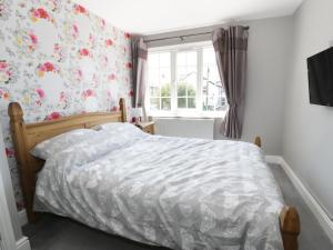 a bedroom with a bed with a floral wallpaper at West Shore Cottage in Llandudno