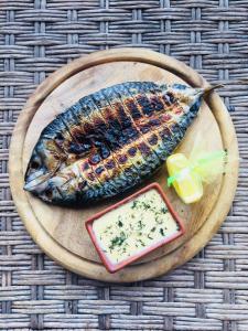 a fish on a wooden plate with a dish of cheese at Dikii Med in Geletintsy