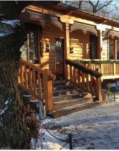 Cabaña de madera con escalera que conduce a un porche en Dikii Med, en Geletintsy