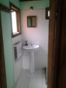 baño con lavabo blanco y ventana en Ligustrum House, en Punta del Diablo