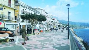 two people walking down a street next to the water at B&B Stella Maris in Diamante +7 photos