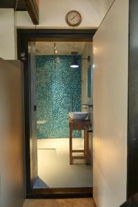 La salle de bains est pourvue d'un lavabo et d'une horloge murale. dans l'établissement Bed in Beek, à Beek