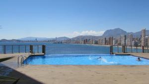 dwie osoby w basenie z miastem w tle w obiekcie Precioso piso con unas vistas increíbles w mieście Benidorm