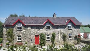 una vieja casa de piedra con una puerta roja en Tig Rua en Killarney