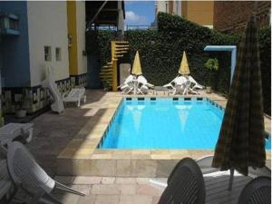 a swimming pool with chairs next to a building at Rede Andrade Porto Mar in Maceió