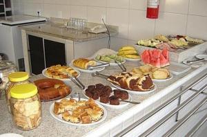 a counter with many different types of pastries on plates at Rede Andrade Porto Mar in Maceió
