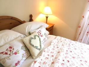 a bed with two pillows with a heart on it at Dolmurgoch Snowdonia Cottage in Dolwyddelan