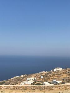 a group of white buildings on a hill next to the ocean at Windmill Villas in Artemonas