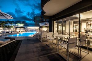 een patio met een zwembad en tafels en stoelen bij Garden City Resort in Kalamata