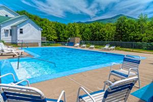 uma piscina com cadeiras e montanhas ao fundo em Parker's Motel em Lincoln