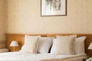 a bed with white pillows and a picture on the wall at Hotel Downtown in Sofia