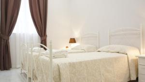 2 camas blancas en un dormitorio blanco con ventana en Ivory Suite Valletta, en La Valeta