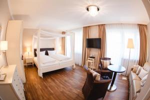 ein Hotelzimmer mit einem Bett und einem Wohnzimmer in der Unterkunft HIRSCH1783 Hotel LANDHAUS in Langenargen
