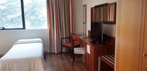 a hotel room with a bed and a desk with a television at Hotel Restaurante El Valles 4 ESTRELLAS in Briviesca