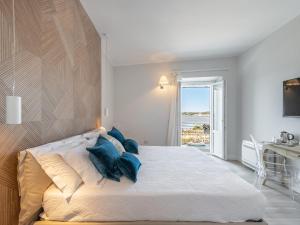 a bedroom with a large white bed with blue pillows at AQUAMADRE Suites in Carloforte