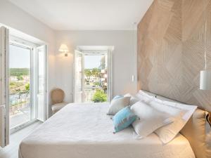 卡洛福泰AQUAMADRE Suites的一间带大床和窗户的白色卧室