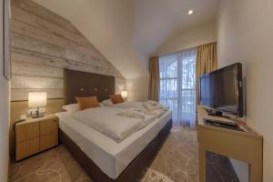 a bedroom with a large bed and a flat screen tv at Aquamaris Strandresidenz Rügen in Juliusruh