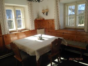 uma sala de jantar com uma mesa e duas janelas em Almurlaub Buchebnerreith, Ferienwohnungen em Hinterstoder
