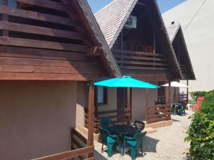 a patio with a table and a blue umbrella at Casutele Intim in Costinesti