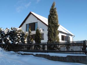 a white house with a fence in the snow at Vila Poule in Bohutín