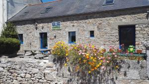un edificio de piedra con flores delante en Chambres d'hotes Ti ar raniged, en Beuzec-Cap-Sizun