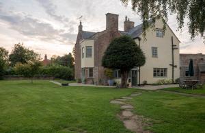 a large white house with a tree in the yard at Churchend Farm Bed and Breakfast in Slimbridge