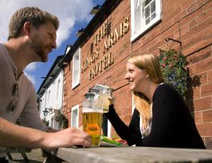 un hombre y una mujer sentados en una mesa con una cerveza en The Kings Arms Temple Sowerby, en Temple Sowerby