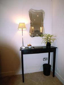 a table with a lamp and a tv on a wall at Panfield House in Braintree