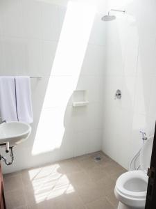 a white bathroom with a toilet and a sink at Plawa Bali Guest House in Canggu