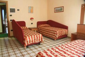 a hotel room with two beds and a chair at Hotel Gaggiano in San Giovanni Rotondo