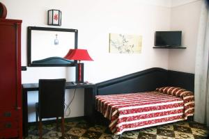 a bedroom with a bed and a desk with a lamp at Hotel Gaggiano in San Giovanni Rotondo