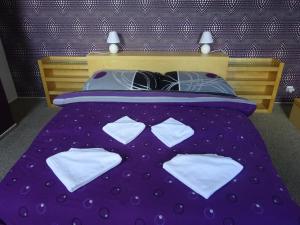 ein violettes Bett mit Bettwäsche und Kissen aus Polyka in der Unterkunft Sunny apartmány Veľká Lomnica in Veľká Lomnica