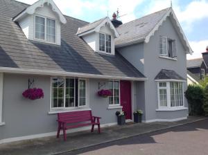 una casa con un banco rojo delante de ella en The Well Bed & Breakfast, en Clonakilty