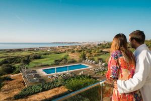 a man and a woman standing on a balcony looking at the ocean at Palmares Beach House Hotel - Adults Only in Lagos